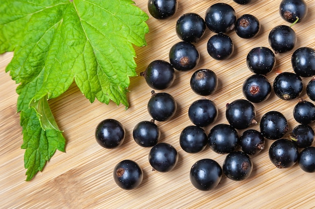 Fresh ripe black currants heap on wooden table with leaf