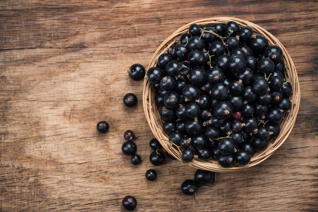 Fresh ripe blackcurrant in basket copy space on wooden board