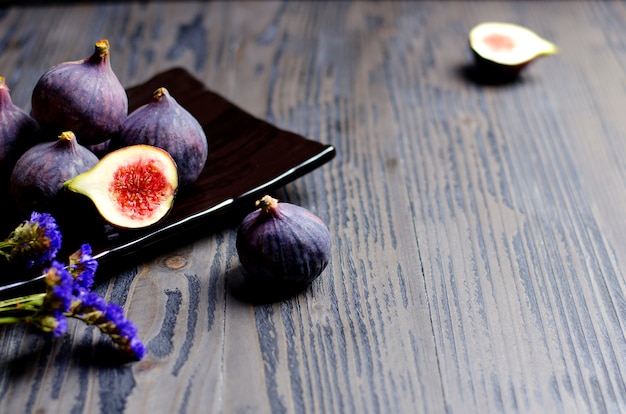 Fresh ripe figs and cut pieces of figs on dark plate