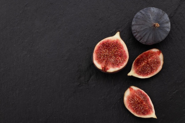 Fresh ripe figs on dark background, top view with copy space.