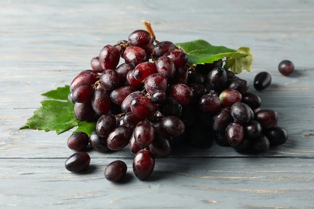 Fresh ripe grape with leaves on gray wooden table