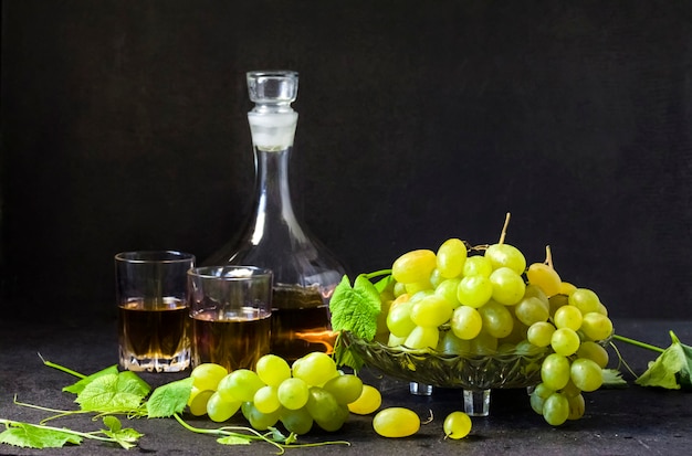 Fresh ripe grapes in a fruit bowl and decanter with grape juice  on black background. Copy space