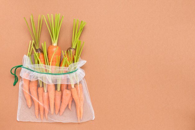 Fresh ripe and juicy carrot in reusable eco-friendly mesh bags.