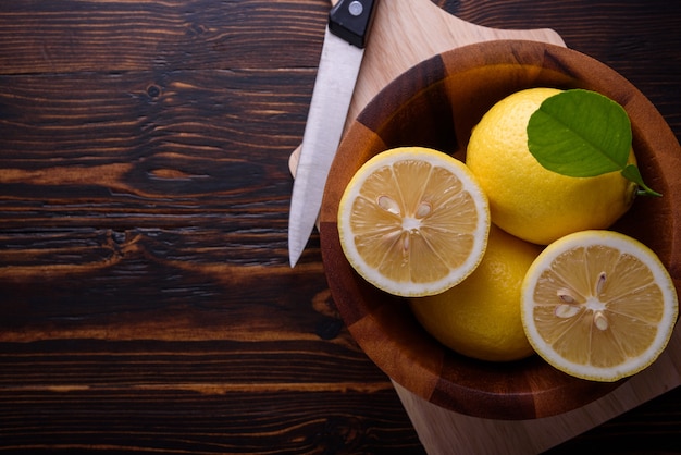 Fresh ripe lemons and knife on wooden table. Top view with copy space