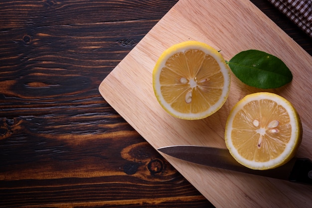 Fresh ripe lemons and knife on wooden table. Top view with copy space