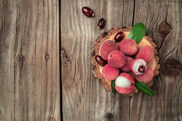 fresh ripe lychee fruit and peeled lychee with green leaves on a wooden background banner menu recipe place for text top view