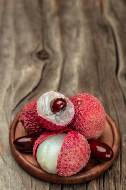 fresh ripe lychee fruit and peeled lychee with green leaves on a wooden background banner menu recipe place for text top view