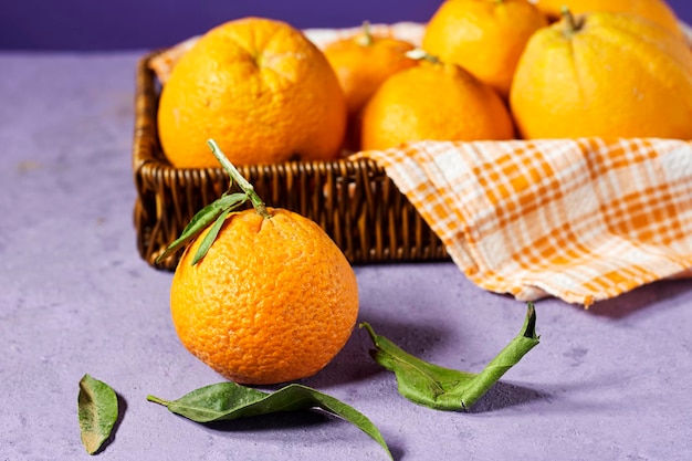 Fresh ripe mandarine in basket near purple background