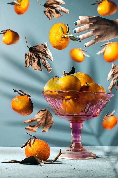 Fresh ripe mandarine with autumn leaves falling in the air and some in stand plate and hand catching