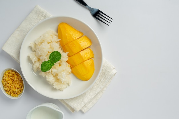 Fresh ripe mango and sticky rice with coconut milk on white surface