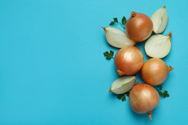 Fresh ripe onion and parsley on blue background