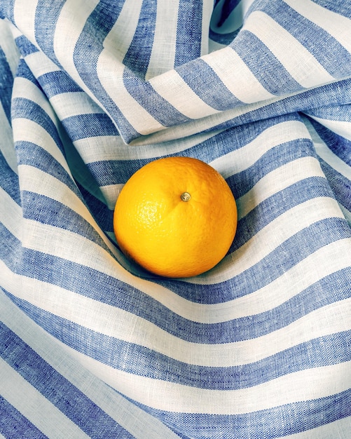 Fresh ripe orange on a striped textile background Healthy season fruits with lots of vitamins