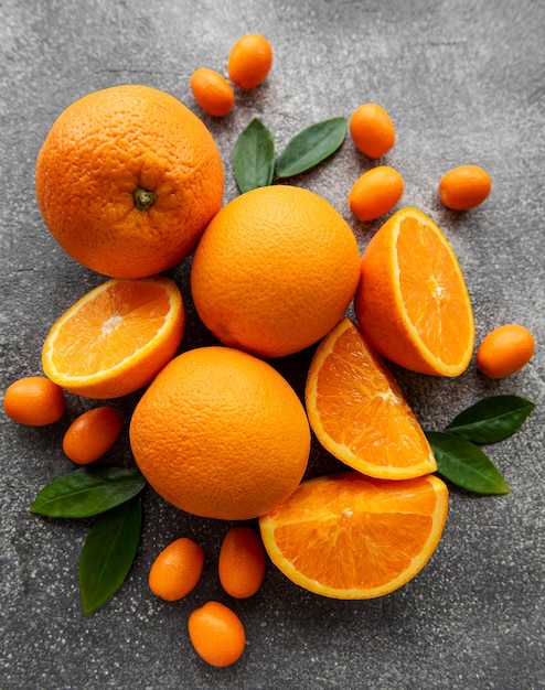 Fresh ripe oranges and kumquat on dark background