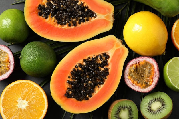 Fresh ripe papaya and other fruits on black table flat lay