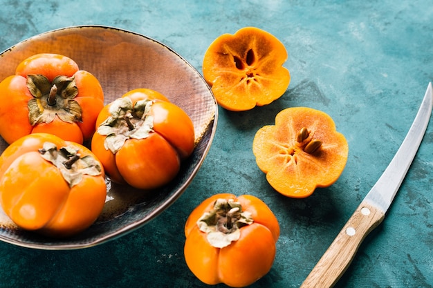 Fresh ripe persimmon on blue .