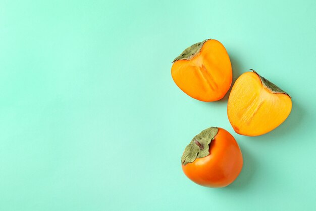 Fresh ripe persimmon on mint background, space for text