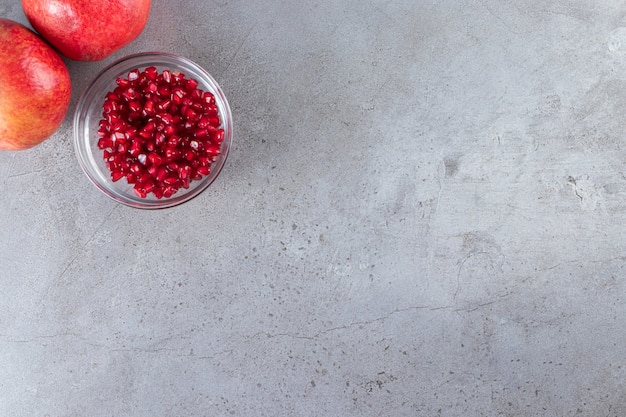 Fresh ripe pomegranates with seeds placed on stone background. 