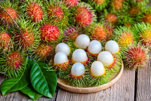 Fresh and ripe rambutan sweet tropical fruit peeled rambutan with leaf Rambutan fruit on plate and wooden background harvest from the garden rambutan tree