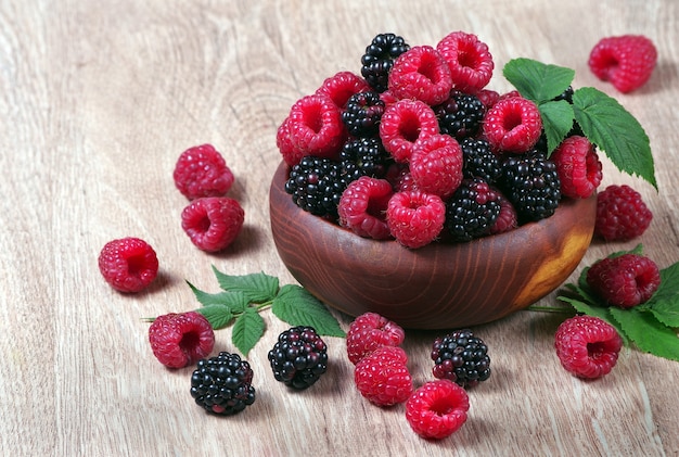 fresh ripe raspberries and blackberries on a wooden table.