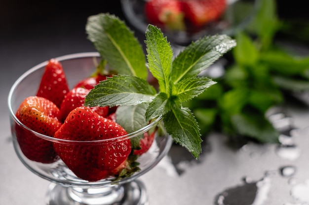 Fresh ripe red strawberries in a glass bowl on black 