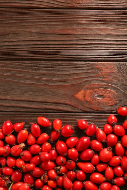 Fresh ripe rosehip berries on wooden table flat lay Space for text