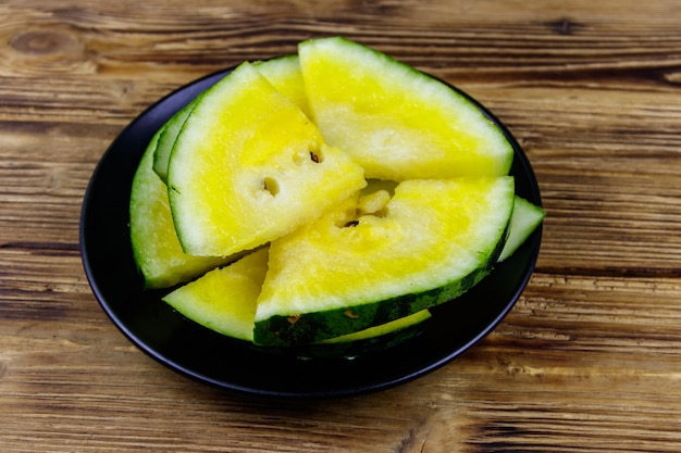 Fresh ripe sliced yellow watermelon in a plate on a wooden table