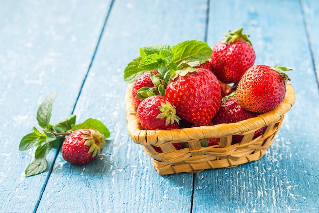 Fresh ripe strawberries in a basket and mint on a table