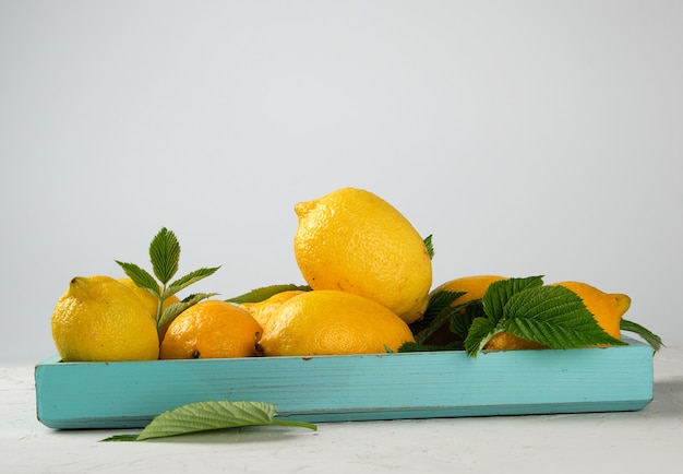 Fresh ripe whole yellow lemons on a blue wooden board