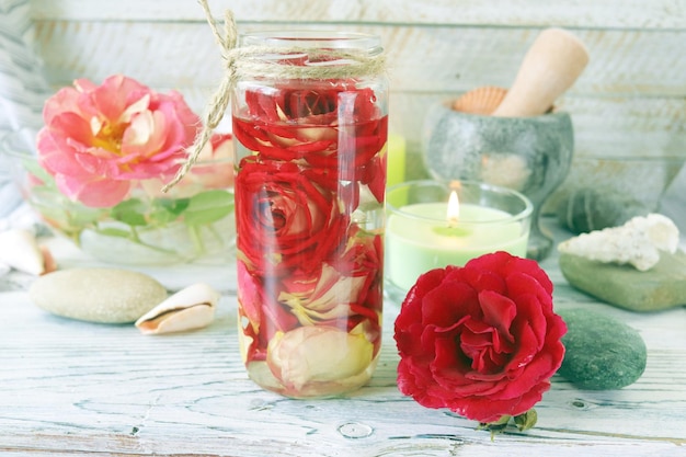 Fresh rose flowers and petal tincture, sea shells and stones, burning candles, spa concept, natural