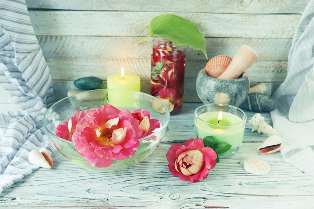 Fresh rose flowers and petal tincture, sea shells and stones, burning candles, spa concept, natural