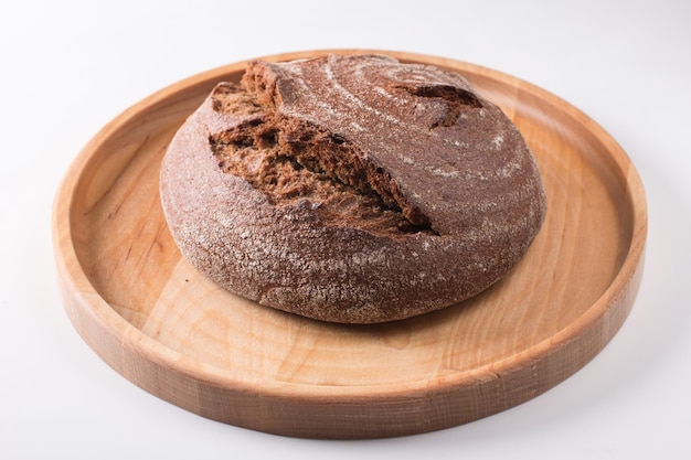 Fresh round black bread with a crispy crust Closeup on a white background