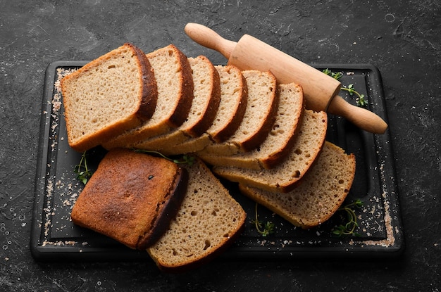 Fresh rye black bread Top view Black stone background rustic style