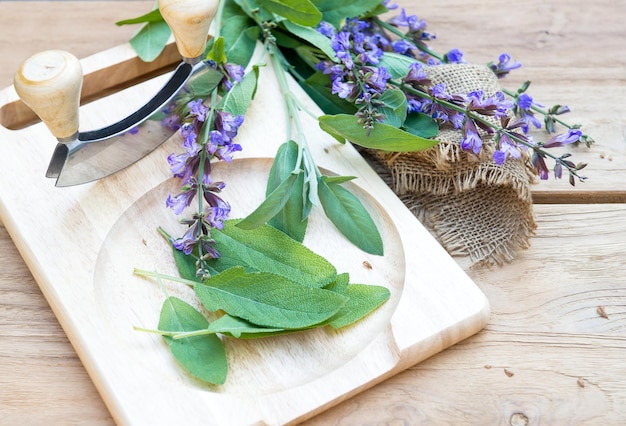 Fresh sage leaves and blossoms on wooden cutting board