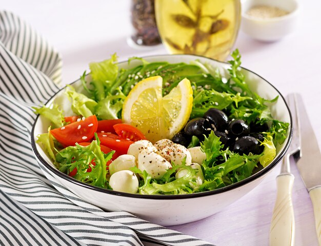 Fresh salad with avocado, tomato, olives and mozzarella in a bowl. 