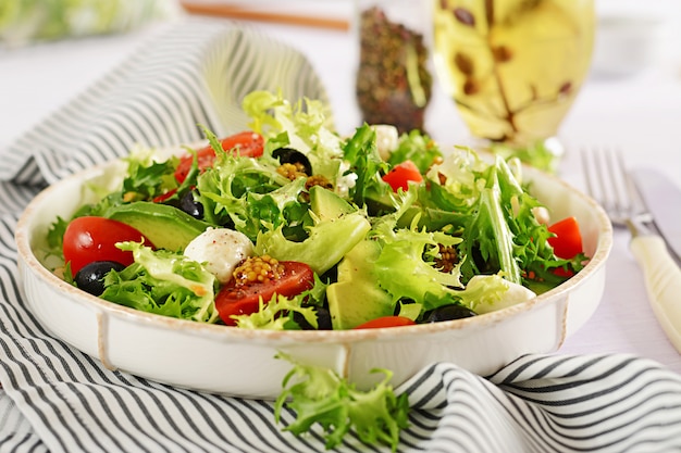 Fresh salad with avocado, tomato, olives and mozzarella in a bowl.