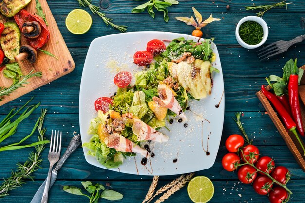 Fresh salad with bacon avocado and tomatoes On a wooden background Top view Copy space