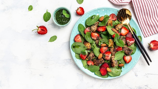 Fresh salad with chicken liver, spinach, strawberries, almond and mint