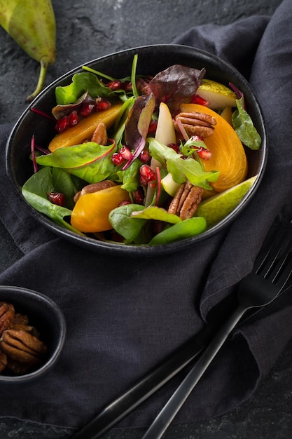 Fresh salad with fruits and greens on black background Healthy food