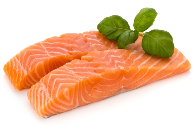 Fresh salmon fillet with basil on the white surface.