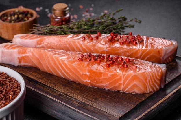 Fresh salmon fillets on black cutting board with herbs and spices