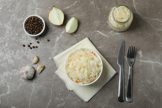 Fresh sauerkraut and ingredients on gray textured table