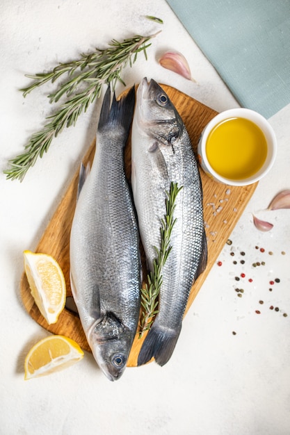 Fresh sea bass fish and ingredients for cooking, lemon and rosemary. White background top view.