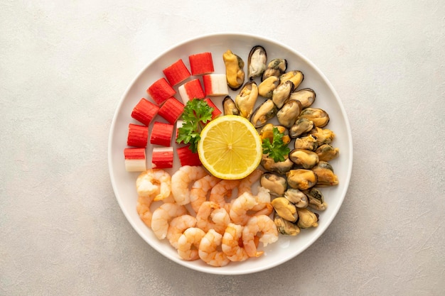 Fresh seafood charcuterie shrimps mussels and crab sticks in plate bright background top view