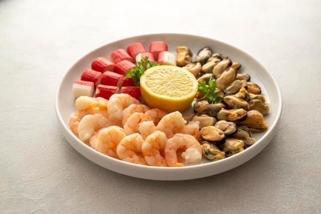 Fresh seafood charcuterie shrimps mussels and crab sticks in plate bright background top view