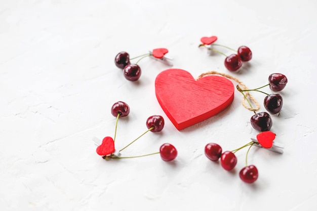 Fresh seasonal red cherry berry fruit with healthy vitamins on white background and red heart as love symbol of valentines day holidayLove is cure Valentine's Day inspiration