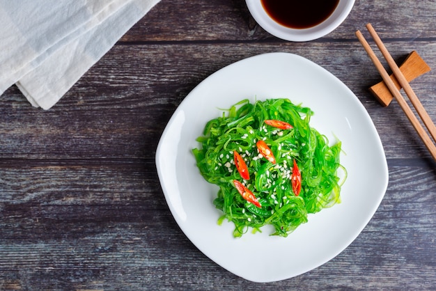 Fresh seaweed salad with soy sauce and white sesame, healthy vegetarian food. Top view with Copy space.