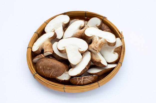 Fresh shiitake mushrooms in basket on white surface