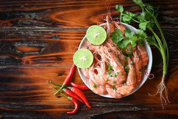 Fresh shrimps prawns seafood lemon lime with herbs and spice shrimp on white bolw and wooden background dining table food