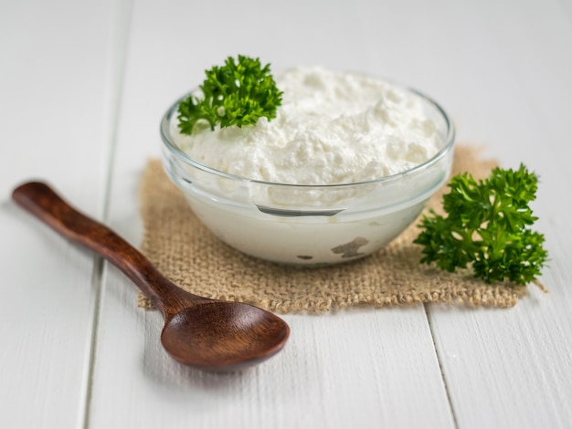 A fresh slice of bread smeared with cottage cheese cream with parsley on the table.