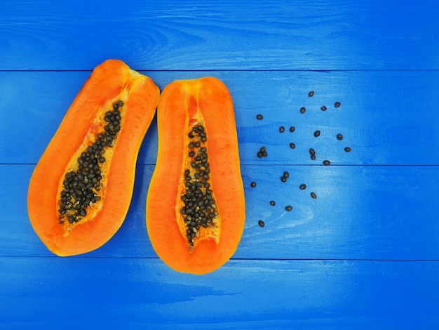 Photo fresh sliced half papaya isolated on blue wood background.